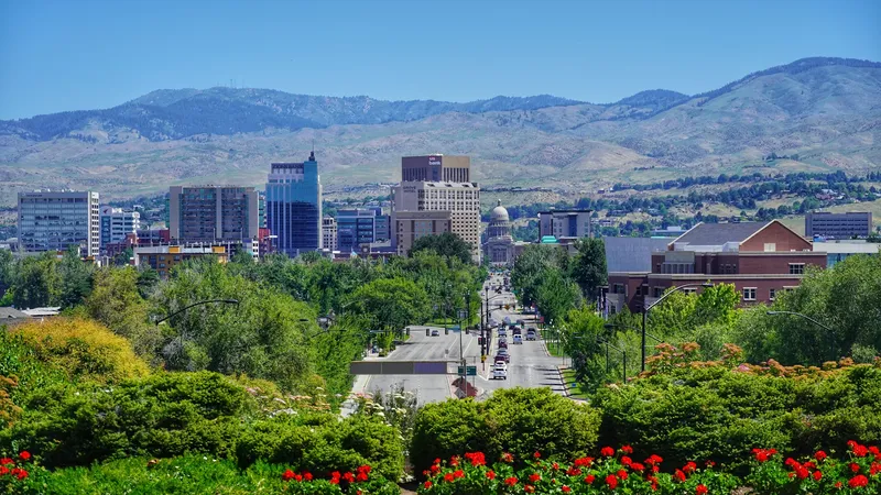 A scenic daytime view of greenery and a busy road in Boise, Idaho with mountains in the background